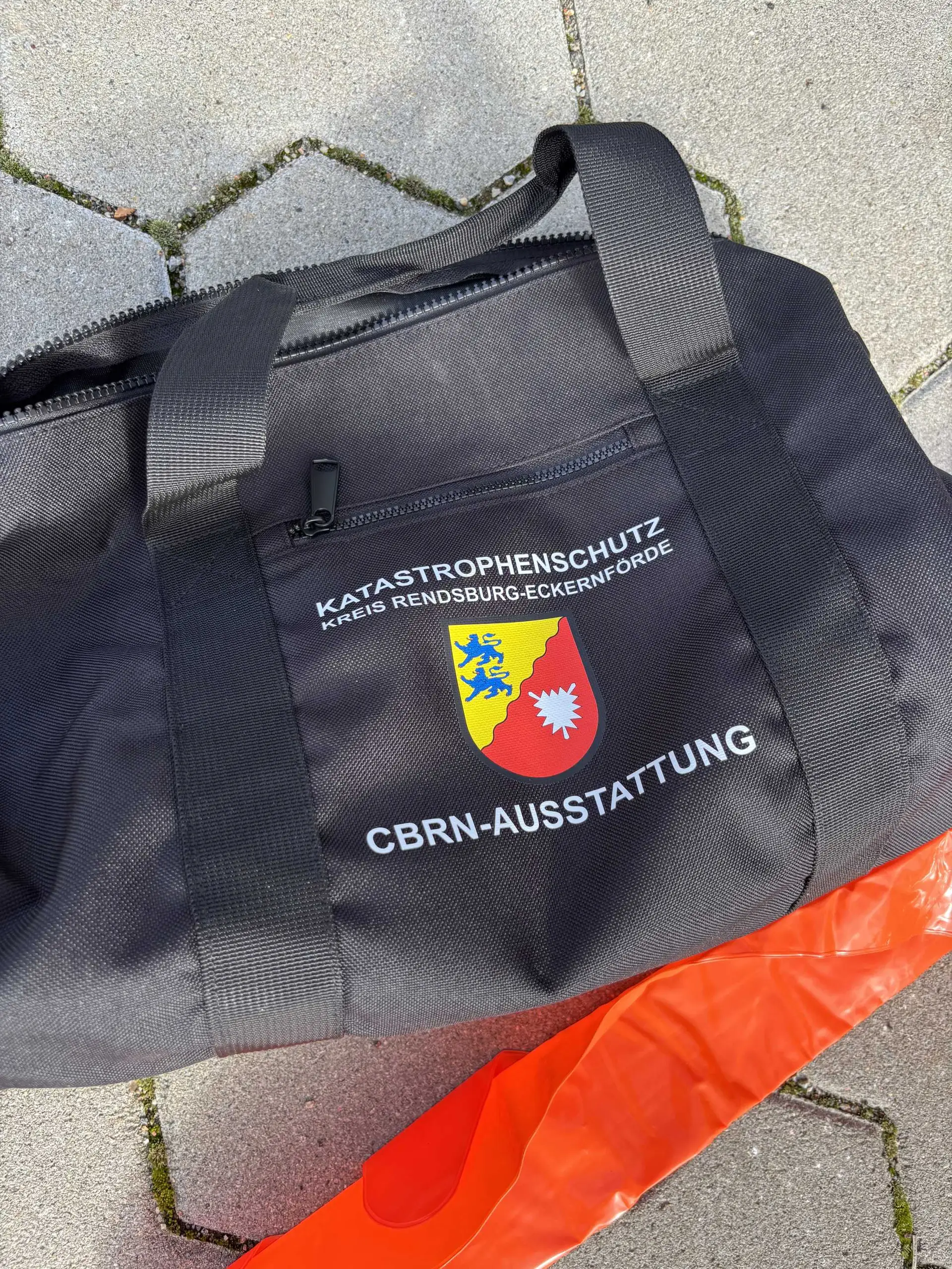 Person trägt Ganzkörperschutzanzug mit Atemschutz und Maske bei einer Übung zum CBRN-Schutz.