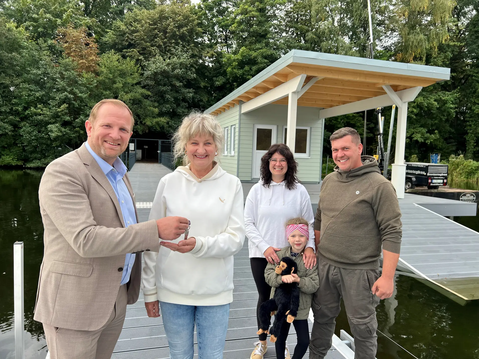 Bürgermeister Toni Köppen übergibt die Schlüssel für das neue Bootshaus am Großen Segeberger See an Mieterin Kerstin Barth und ihre Familie.